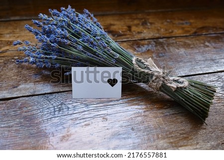 Mockup of a greeting card or card for wishes and a bouquet of lavender on a wooden background. Greeting card. Bouquet of fragrant lavender. Place for text 