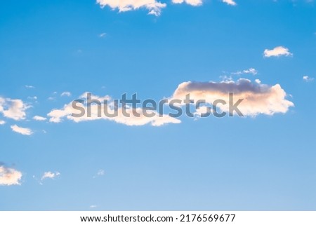 Cloud being illuminated by pale yellow ray of the sun in clear morning sky during sunrise golden hour. Beauty of the nature concept.