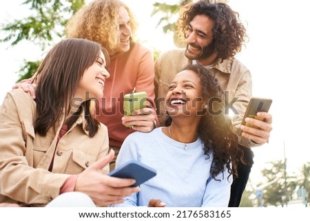 Happy friends using mobile and laughing. Smiling people holding smart phones. Youth culture and technology online concept. Royalty-Free Stock Photo #2176583165
