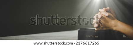 Banner image of Hands folded in prayer in church concept for faith, spirituality and religion, woman praying on holy bible.
