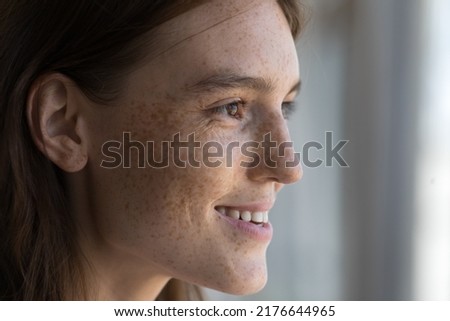Side profile attractive face of young female, smooth skin covered with freckles, woman staring into distance daydreaming smile enjoy view close up cropped image. Vision, eyesight care, youth concept Royalty-Free Stock Photo #2176644965