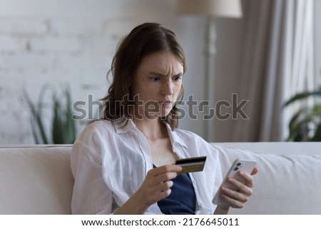 Young woman hold credit card and smartphone try pay via e-bank application experiences problem, feels annoyed. Lack of money, insecure unsuccessful payment, fraud, insufficient funds for e-pay concept Royalty-Free Stock Photo #2176645011