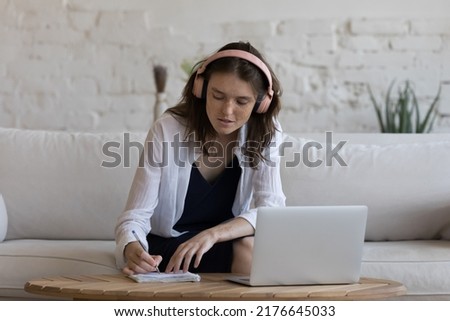Self-education, improve knowledge using internet, effective study on-line, e-learn, modern tech concept. Young woman in headphones listen course, make task looks focused sit on sofa at home use laptop