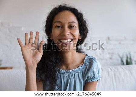 Head shot portrait African woman sit on sofa smile looks at camera make video conference, greets friend, talks to family living abroad, enjoy remote communication. Modern tech, videocall event concept Royalty-Free Stock Photo #2176645049