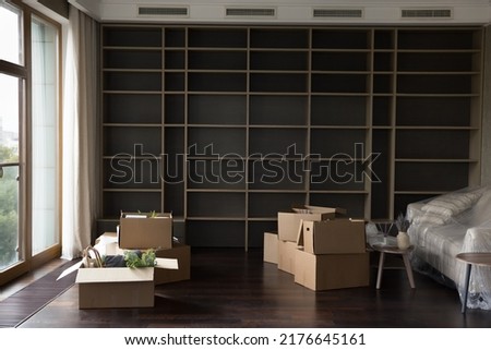 Cardboard boxes for moving with household staff stacked on floor in empty living room with nobody, Cargo, containers delivered into new house for unpacking. Relocation, renovation concept Royalty-Free Stock Photo #2176645161