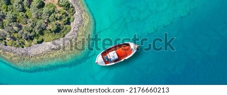 Aerial drone top down ultra wide photo of beautiful red fishing boat anchored in small paradise island of Monolia in small complex of Lihadonisia with turquoise clear sea, North Evia island, Greece