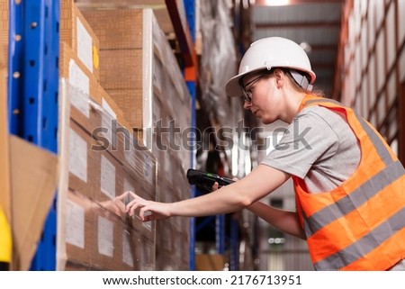 Female workers in safety helmet using scanner checking inventory stock at warehouse. Retail warehouse with full shelves of goods cardboard boxes, Product Distribution Delivery Center.