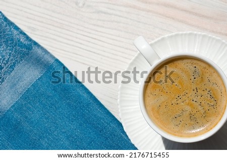 A cup of coffee and a saucer on a white table. Romantic morning still life.