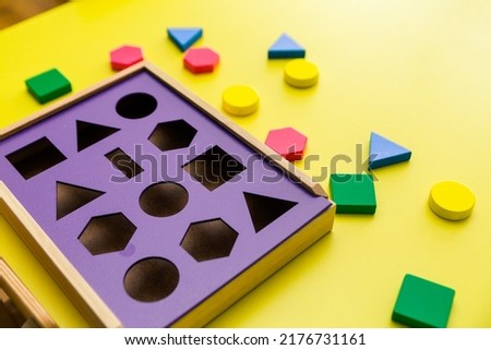 Baby sorter with geometric figures from wood on a yellow isolated background. Horizontal photo