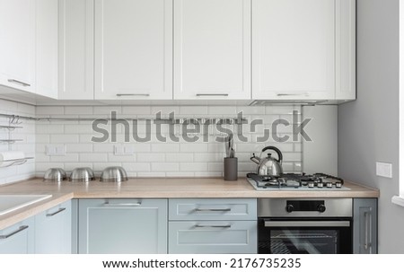 Design of a modern small light white kitchen with a blue kitchen cabinets and loft lamps Royalty-Free Stock Photo #2176735235