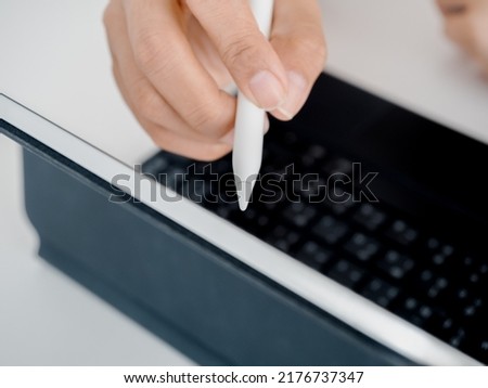 Close up hand holding and write, draw or sign on digital tablet screen, computer on white table. Business and technology concept.