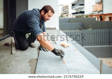 industrial worker, handyman installing big ceramic tiles on bathroom walls. Balcony area covered in ceramic tiles with strong adhesive Royalty-Free Stock Photo #2176740229