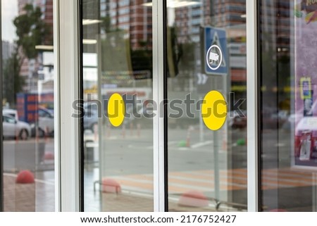 Supermarket automatic glass doors with camera sign closeup.