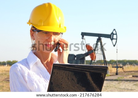 Business woman in an oilfield talking on cell phone