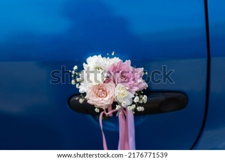 Wedding boutonniere on the handle of a blue car. Designer floral decoration.