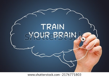 Hand writing Train Your Brain on drawn human brain with white marker on transparent glass board. Royalty-Free Stock Photo #2176771803