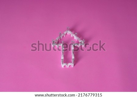 Plastic cable clips forming directional signs on a bright pink background