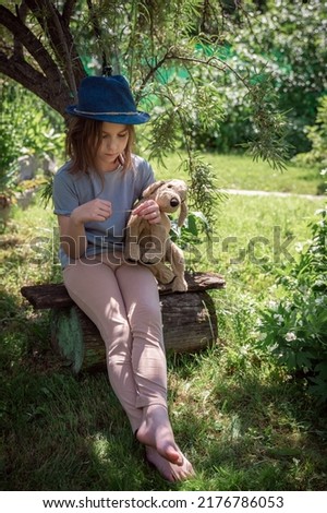 cute girl with a toy dog sitting under a tree