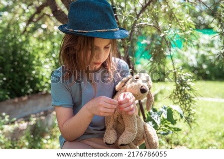 cute girl with a toy dog sitting under a tree