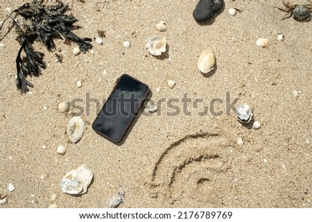 Wi-Fi sign is drawn on the sand next to a smartphone, on the seashore, on a sunny summer day. Top view. 