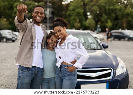 Joyful Black Family Showing New Car Key Posing Standing Near Luxury Auto Outdoor, Smiling To Camera. Parents And Daughter Celebrating Buying Vehicle. Automobile Leasing And Ownership Royalty-Free Stock Photo #2176793223