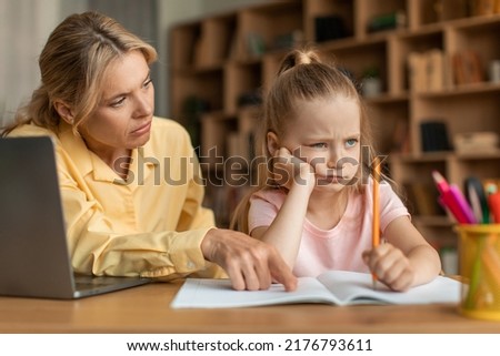 Strict mother scolding upset daughter for bad marks or school exam results, mum lecturing unmotivated girl, pointing to notebook. Generations, parent and child conflict Royalty-Free Stock Photo #2176793611