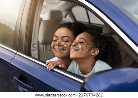 Happy African American Mom And Daughter Sitting In Car Smelling Fresh Air In Opened Window, Enjoying Road Trip Together. Family Traveling By Automobile. Transportation, Vehicle Ownership Concept Royalty-Free Stock Photo #2176794261