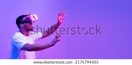 Young African American Guy Touching Air While Having Virtual Reality Experience In VR Glasses Headset, Black Man Enjoying Video Games, Standing In Vivid Neon Light Over Purple Background, Collage