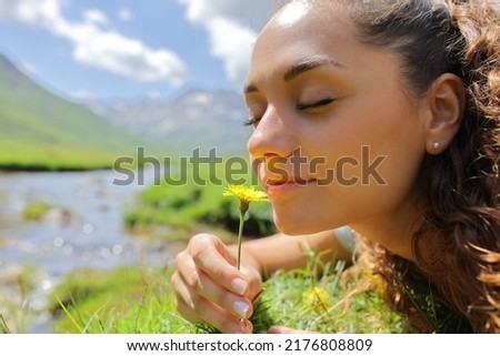 Portrait of a woman smelling a flower in the mountain in a riverside Royalty-Free Stock Photo #2176808809