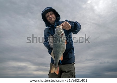 Perch fishing. Fisherman look at big perch fish skeptical Royalty-Free Stock Photo #2176821401