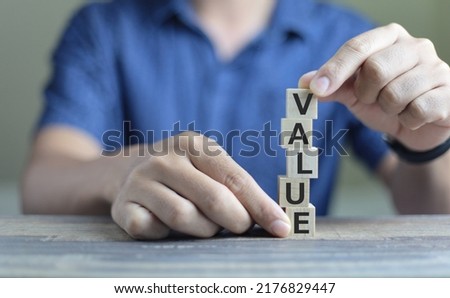 Businessman building Wood cube block with word VALUE on table. Growth business for success concept.