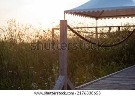 Wooden terrace with sun umbrella at sunset yellow light at summer evening