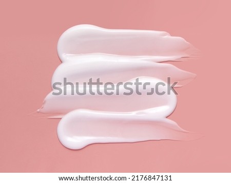 White cosmetic cream lotion swatch smear smudge on pink color background. 