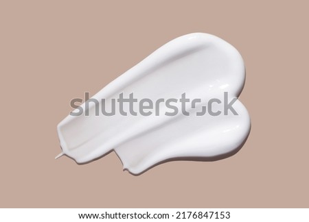 White cosmetic cream lotion swatch smear smudge on brown color background.  Royalty-Free Stock Photo #2176847153