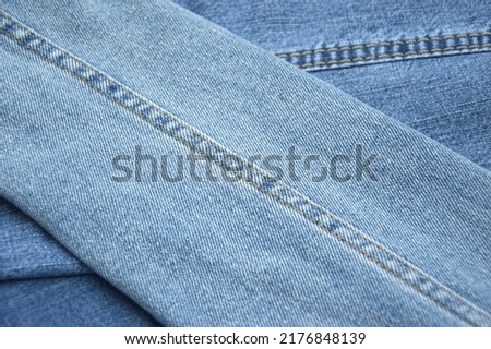 Lots of jeans pants in a stack. Denim background. The concept of buying, selling, shopping and trendy modern clothes.