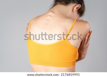 Intervertebral spine hernia, pain between the shoulder blades, woman suffering from backache, spinal disc disease on gray background Royalty-Free Stock Photo #2176859991