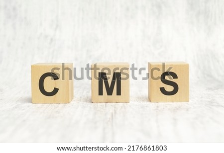 CMS letters of wooden blocks in pillar form on white background, copy space