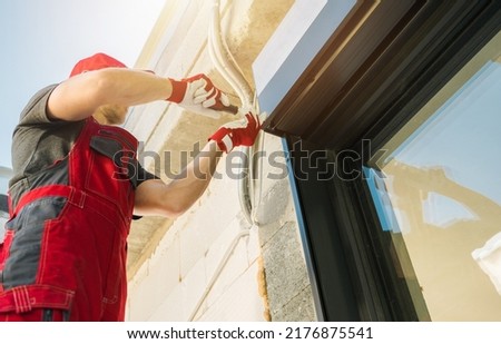 Electric Exterior Window Roller Shutters Installation Performed by Professional Caucasian Shutters Technician. Royalty-Free Stock Photo #2176875541
