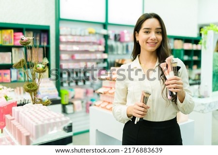 Gorgeous salesperson showing the new makeup brushes while selling products at the store Royalty-Free Stock Photo #2176883639