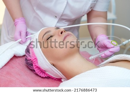 Woman getting face peeling procedure in a beauty SPA salon. Rejuvenating facial gas liquid treatment.  Hydro air skin cleansing operation. Close up, selective focus. Royalty-Free Stock Photo #2176886473
