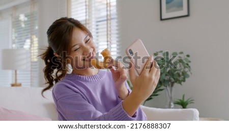 Young vlogger asia people influencer girl take photo eat bite smiley donut funny face post review on   reel app Sweet tooth food sugar lover enjoy fun show viral video camera at home Royalty-Free Stock Photo #2176888307
