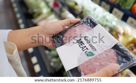 Close-up hand carry choose zero pork soy bean faux peas cutlet gluten free read beyond non-meat lab label. Buy raw fake beef tray in asia store veggie burger patty for health care eat diet meal cook. Royalty-Free Stock Photo #2176889755