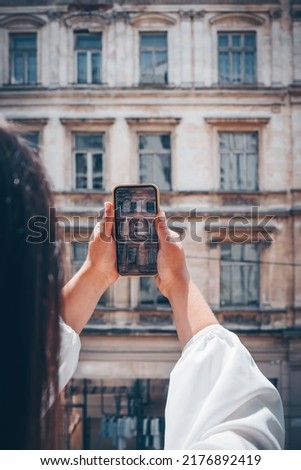 A young girl photographs old buildings. Tourist girl takes photos of the old town.