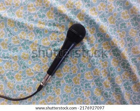 black wired microphone on green fabric with flower pattern. isolated background