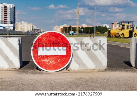 A stop road sign and concrete blocks block the entrance to the construction site. Closed road. Construction and road works
