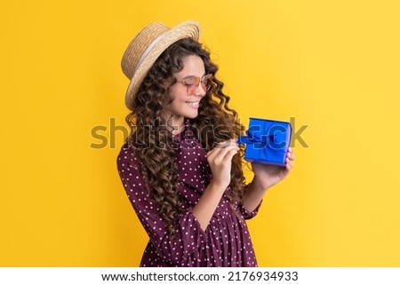 cheerful kid with curly hair hold present box on yellow background