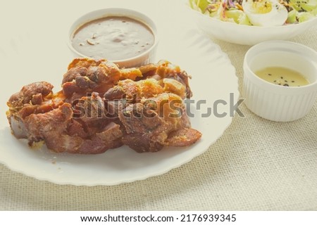 Deep fried pork knuckle with mushroom gravy source, fresh vegetable and salad cream source