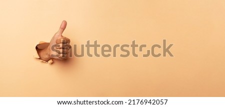 Close-up of male hand showing thumbs up on a brown background.
 Royalty-Free Stock Photo #2176942057