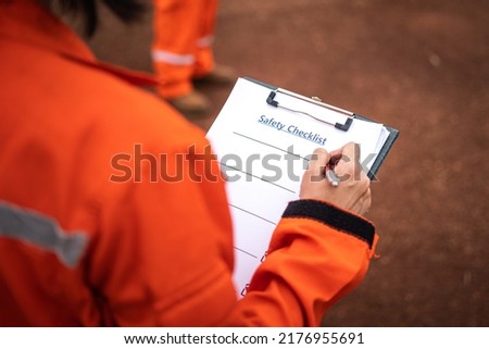 Writing down on safety checklist during perform operation audit. Industrial working action scene. Selective focus.