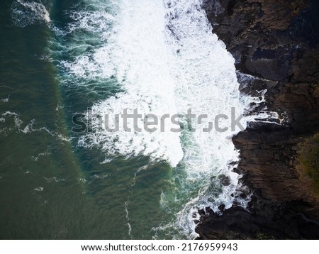 View from above. Beautiful seascape. Turquoise ocean water and white foamy waves crash against the rocky shore. Fresh sea air. Beauty of nature. Ecology. Geology.
